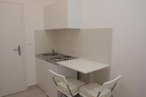 a white kitchen with two chairs and a sink at Apartments Villa Desire in Makarska