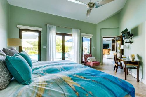a bedroom with a blue bed with a desk and windows at Luxury Villa, Perfect for Groups. Stunning Pool. Allamanda del Mar in Placencia Village
