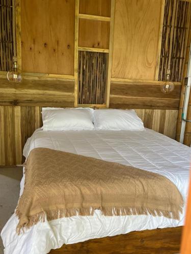 a large bed in a room with wooden walls at Majestic Coffee Hotel and Restaurant Tierradentro in Tierra Adentro