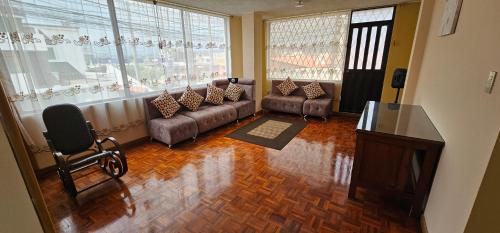 a living room with a couch and a chair and windows at Departamento Bien Ubicado con todo lo necesario in Latacunga