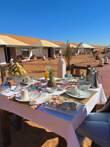 a white table with food on it in the desert at Aladdin merzouga camp in Merzouga
