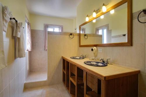 ein Bad mit einem Waschbecken, einem Spiegel und einer Dusche in der Unterkunft Bahia Vista - Spectacular Views - 4 Bedrooms in Placencia Village