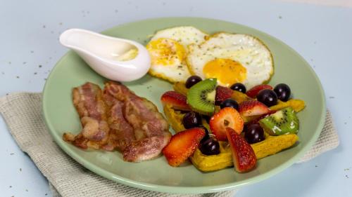 a plate of breakfast food with eggs bacon and fruit at Selva House in Medellín