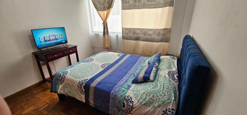 a small bedroom with a bed and a television at Departamento Amplio con todo lo necesario in Latacunga