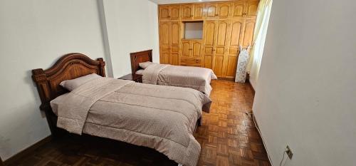 a bedroom with two beds and a wooden door at Departamento Amplio con todo lo necesario in Latacunga