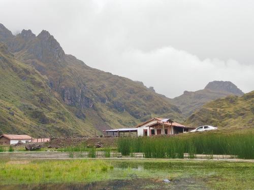 une maison dans une vallée avec des montagnes en arrière-plan dans l'établissement HOMESTAY KINSA COCHA, à Pisac