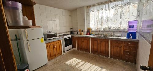 a kitchen with wooden cabinets and a white refrigerator at Departamento Amplio con todo lo necesario in Latacunga