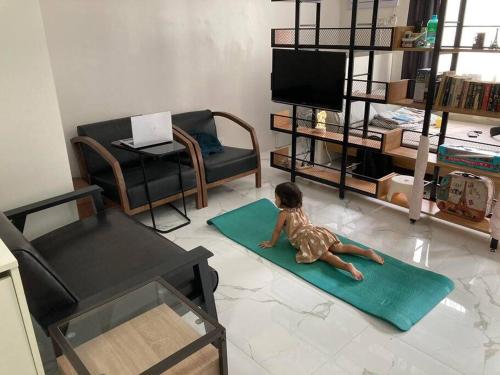 a small child laying on a green rug in a living room at Modern Simplicity: Cozy @Nuvali in Pitland