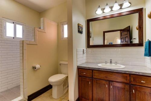 ein Badezimmer mit einem Waschbecken, einem WC und einem Spiegel in der Unterkunft Casa Valencia - Modern Pool Family Luxury Sleeps 8 in Placencia Village