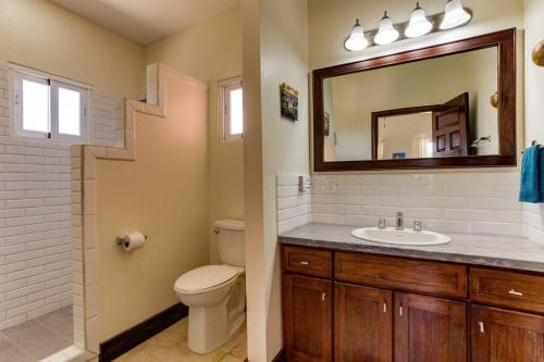 a bathroom with a sink and a toilet and a mirror at Casa Valencia - Modern Pool Family Luxury Sleeps 8 in Placencia Village