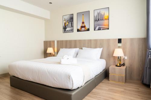 a bedroom with a large white bed with two lamps at indigo Hotel Hatyai in Ban Kohong