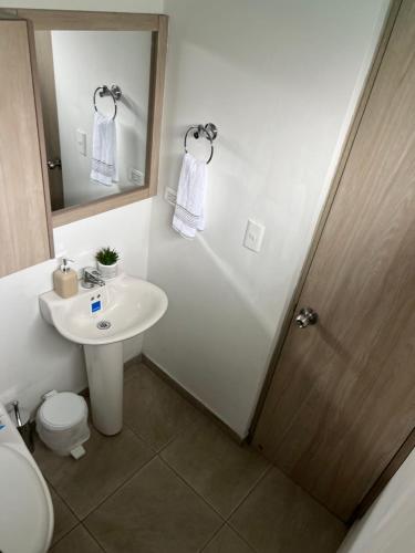 a bathroom with a sink and a toilet and a mirror at Lujoso apartamento central y moderno in Manizales