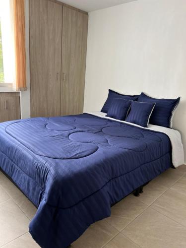 uma grande cama azul num quarto branco em Lujoso apartamento central y moderno em Manizales