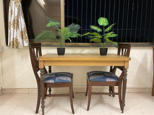 uma mesa de madeira com duas cadeiras e duas plantas em Classy & Cozy 1BHK @ Ville Parle Mumbai em Mumbai