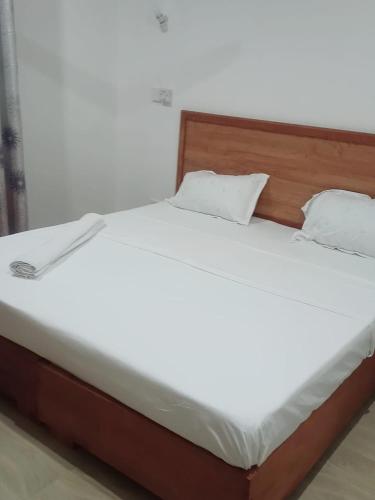 a white bed with a wooden headboard and white pillows at Jade luxury apartments in Galu