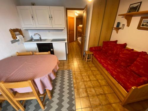 un salon avec un canapé rouge et une cuisine dans l'établissement Appartement à 600m du télésiège de Petit-Châtel, Multi Pass offert, animaux acceptés sur demande. - FR-1-693-15, à Châtel