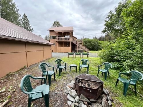 a group of green chairs sitting around a fire pit at Bear Lake Lodgings B&B, Inc in Seward