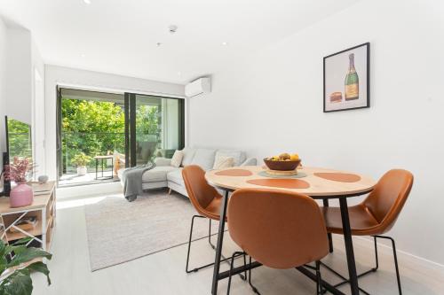 a white living room with a table and chairs at Feel at Home with Aircon, Pool, Gym, WiFi in Auckland