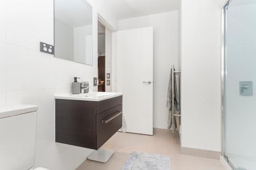 a white bathroom with a sink and a shower at Feel at Home with Aircon, Pool, Gym, WiFi in Auckland