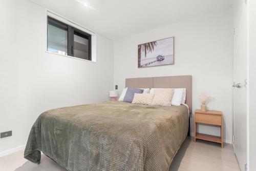 a white bedroom with a bed and a window at Feel at Home with Aircon, Pool, Gym, WiFi in Auckland
