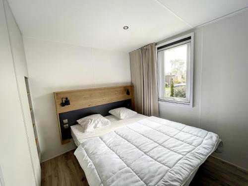 1 dormitorio con 1 cama blanca grande y ventana en Mobil-Home Jullouville, 3 pièces, 4 personnes - FR-1-361A-75, en Jullouville-les-Pins