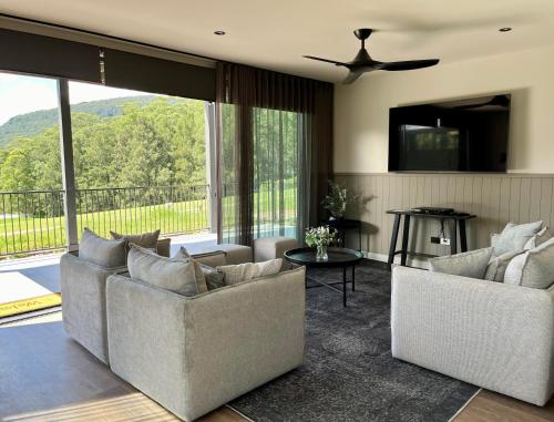 a living room with two couches and a large window at Kangaroo Valley Golf and Country Retreat in Kangaroo Valley