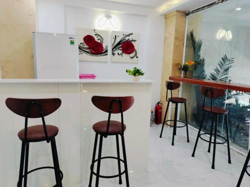 a bar with stools in a room with roses on the wall at Adventure Hotel in Ho Chi Minh City