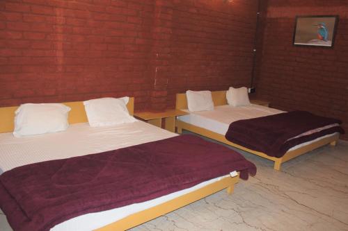 two beds in a room with a red brick wall at corbett jungle safari & homestay in Jhirna