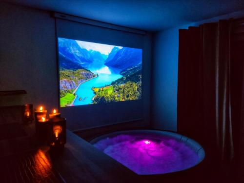 a room with a tv and a tub with purple lighting at Le nid de l'Almont jacuzzi privatif, private jacuzzi Hot Tub near Olympic Games MELUN in Melun