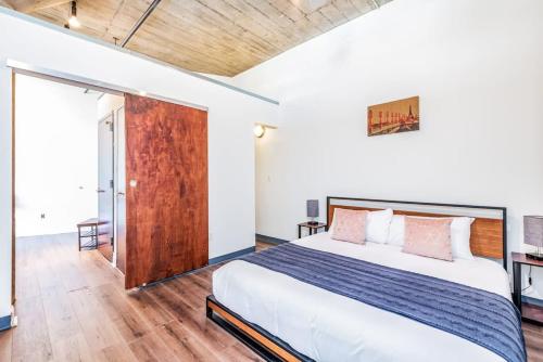ein Schlafzimmer mit einem großen Bett und einer Holztür in der Unterkunft Architect's Stunning loft by CozySuites in Saint Louis