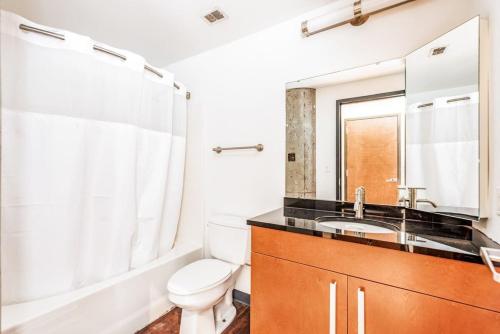 a bathroom with a toilet and a sink and a mirror at Architect's Stunning loft by CozySuites in Saint Louis