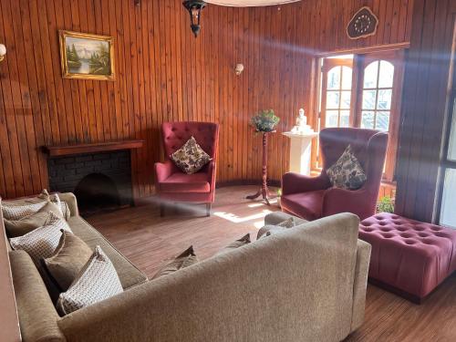 ein Wohnzimmer mit einem Sofa, 2 Stühlen und einem Kamin in der Unterkunft Serendib Hotel in Nuwara Eliya