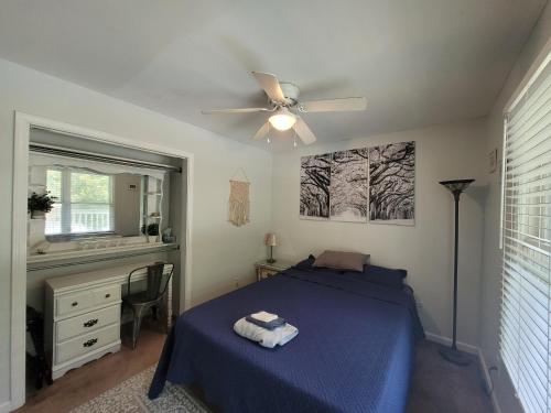 Schlafzimmer mit einem blauen Bett und einem Deckenventilator in der Unterkunft The Yellow Bungalow in Savannah