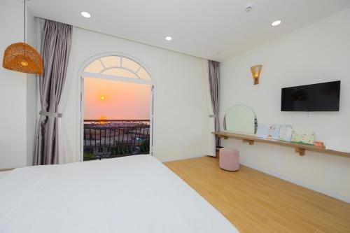 sypialnia z łóżkiem, telewizorem i oknem w obiekcie Lily House Hotel Phu Quoc w Duong Dong