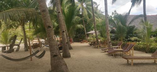 a sandy beach with chairs and palm trees at Sulu Sunset Beach Resort in Nauhang