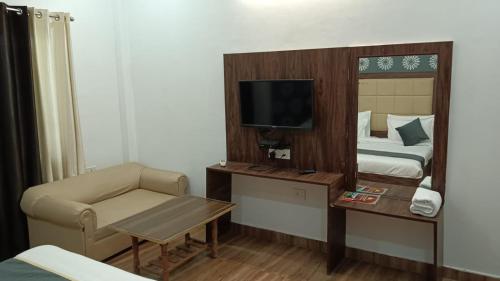 ein Hotelzimmer mit einem Bett, einem TV und einem Stuhl in der Unterkunft Hotel Amrit Resort in Alwar