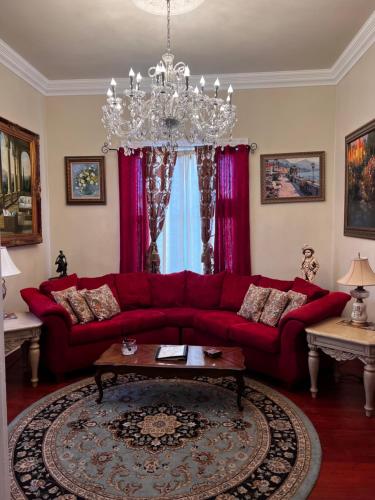 a living room with a red couch and a chandelier at El Amador Inn Downtown Tucson in Tucson