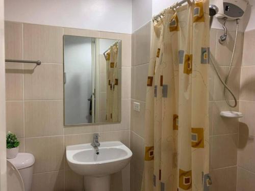 ein Bad mit einem Waschbecken und einem Duschvorhang in der Unterkunft Grand Riviera Suite a4 front of US embassy Dolomite in Manila