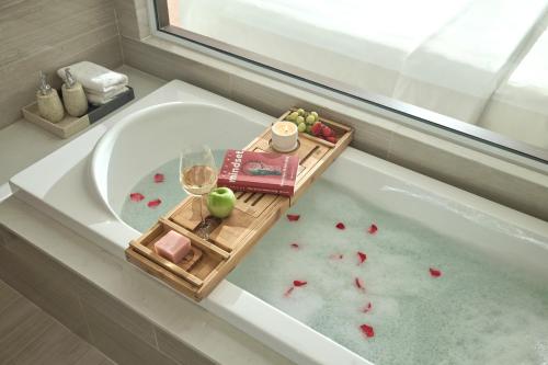 a bath tub with a tray of fruit and a glass of wine at PANAMA Nha Trang Hotel in Nha Trang