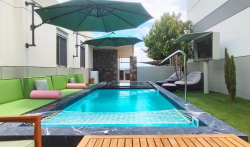 a swimming pool with chairs and an umbrella at Villa Salvia - Country style luxury & a captivating poolscape in Áyiai Paraskiaí
