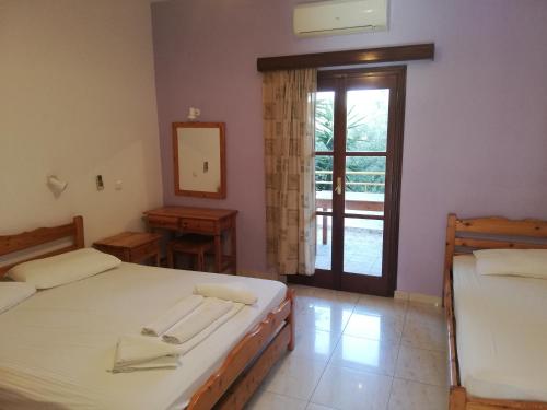 a bedroom with two beds and a door to a patio at Climbing House Annas Apartments in Panormos Kalymnos