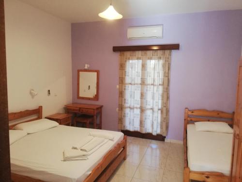 a bedroom with two beds and a mirror and a window at Climbing House Annas Apartments in Panormos Kalymnos