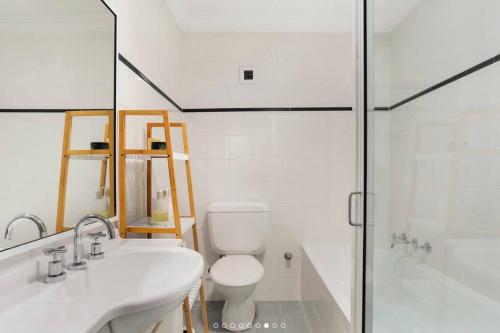 a bathroom with two sinks and a toilet and a shower at Stylish Beachside Sanctuary, steps to the beach in Sydney