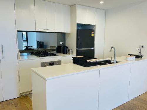 a kitchen with white cabinets and a black refrigerator at Stylish Apartment with city view close to beach airport cbd in Sydney