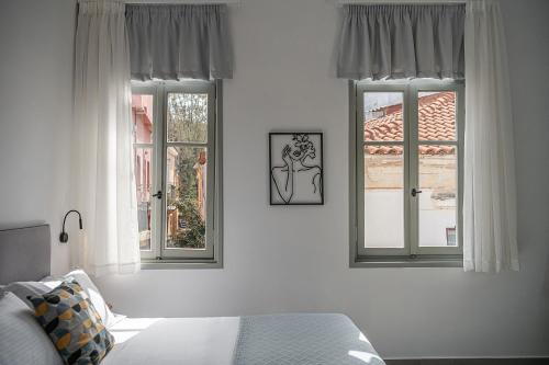 a bedroom with two windows and a bed at Porto Vecchio in Chania Town