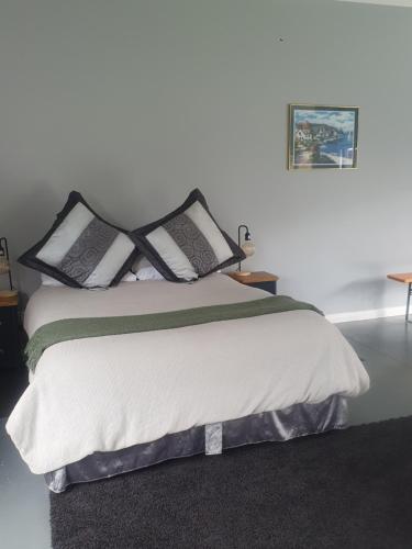 a bed with black and white pillows on it at The Red Shed in Matamata