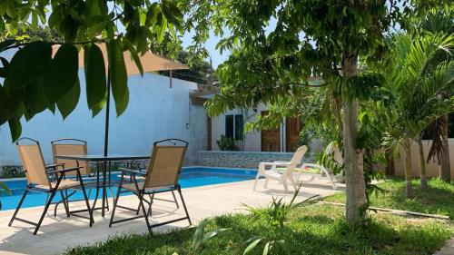 un patio con mesa y sillas junto a una piscina en Casa Terracota en Bacalar