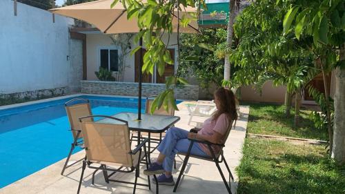 a woman sitting at a table next to a pool at Casa Terracota in Bacalar