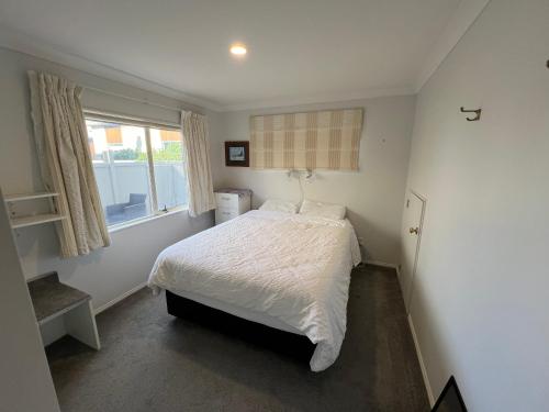 a bedroom with a white bed and a window at Beachside Bliss in Tauranga