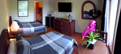 a bedroom with two beds and a table and a dresser at Aurora Suites in Guadalajara